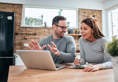 man and woman smiling in front of laptop computer as they explore alumni management software for behavioral health