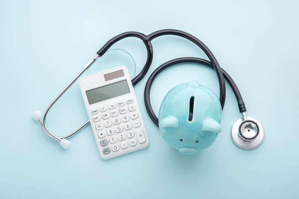 a calculator, piggy bank, and stethoscope represent the benefits of tracking your medical finances