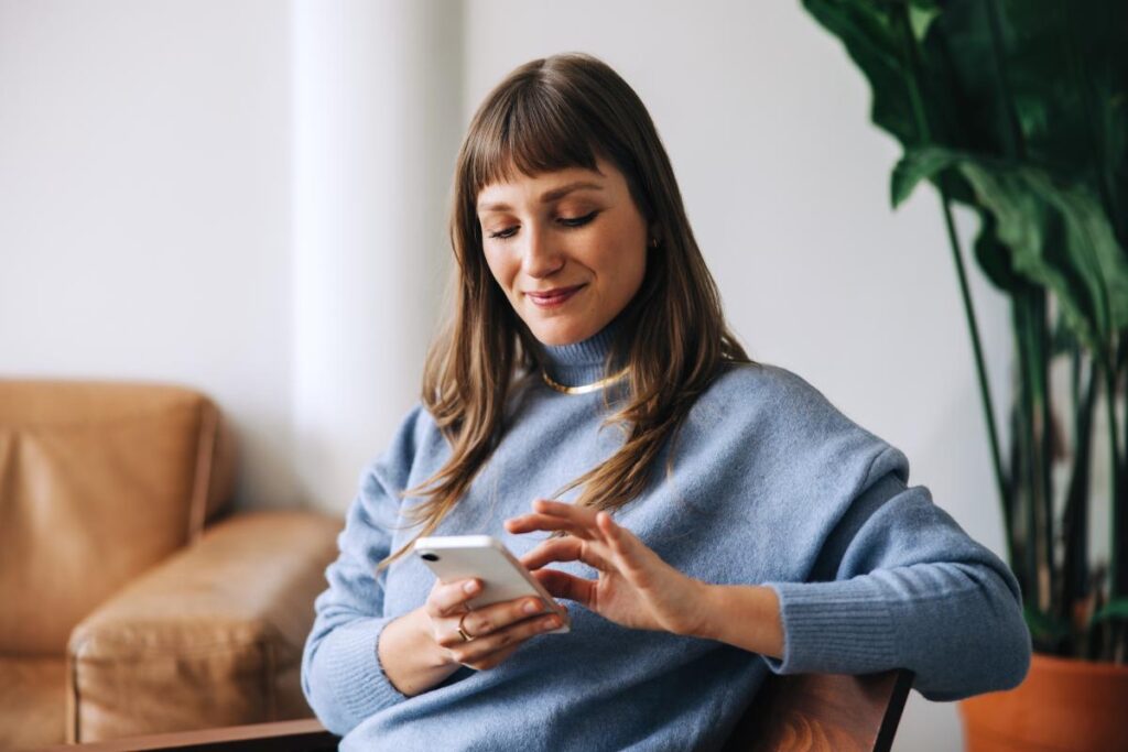 a person uses their phone to research the importance of alumni management software