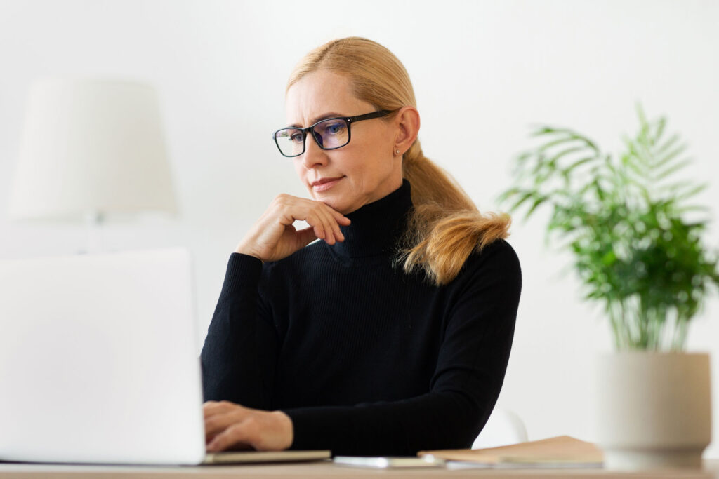 a woman uses a laptop to research behavioral health practice emr software