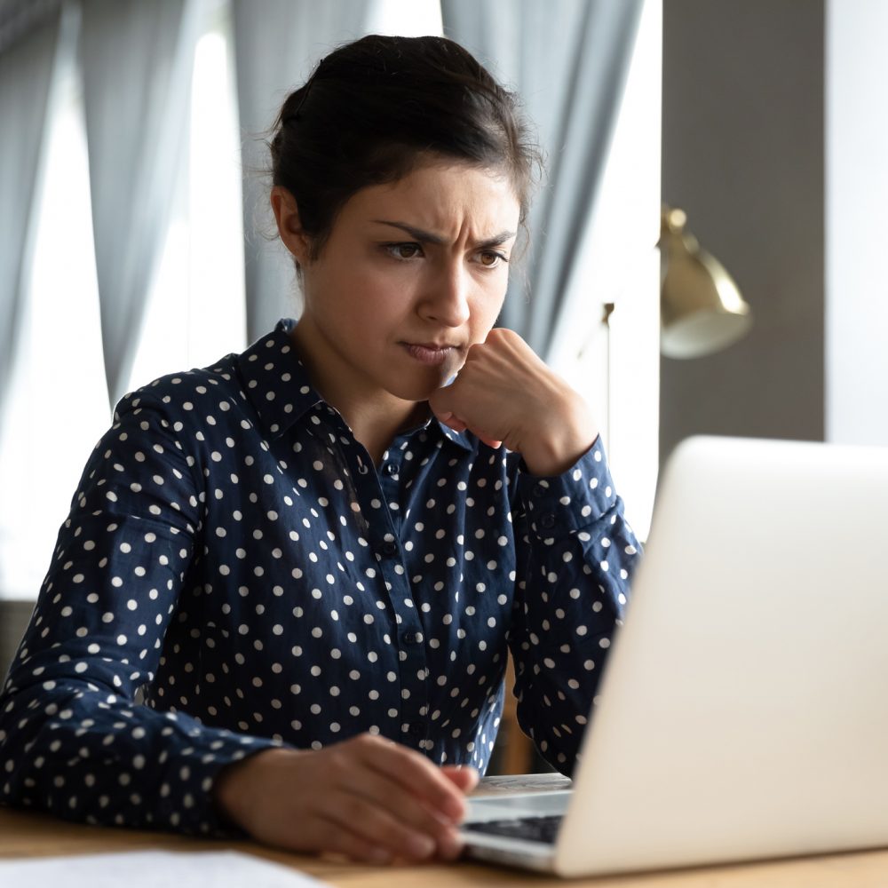 Concerned puzzled young indian woman student professional use look at laptop at home office feel stressed frustrated about computer software problem worried of technology negative online news concept