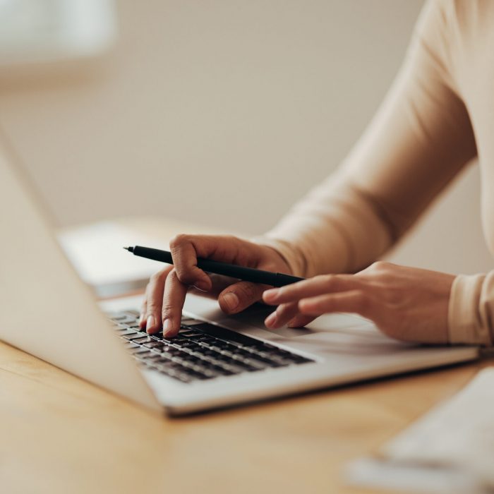 An anonymous Asian businesswoman working on her laptop computer while sitting at desk in her office