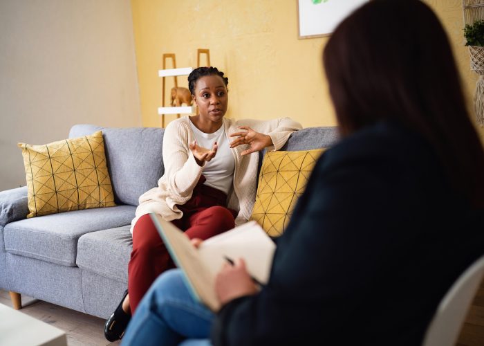 Woman of Black ethnicity, sharing her thoughts and emotion at the therapy, led by the female psychotherapist