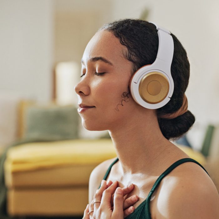 Woman, meditation and yoga in headphones listening to calm music, holistic exercise and peace in living room. Young person with audio podcast, dream of health and relax in spiritual wellness at home