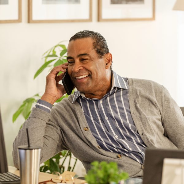 The senior adult manager refers to documents on the desktop PC while on talking with an  employee on the phone.