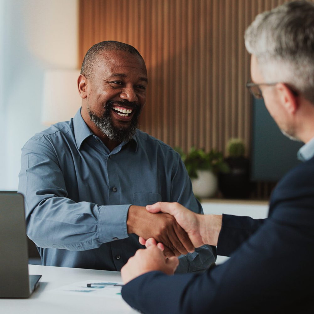 Shaking hands, collaboration and business men in office for partnership, agreement or deal. Happy, meeting and male financial advisor with client for investment contract with handshake in workplace.